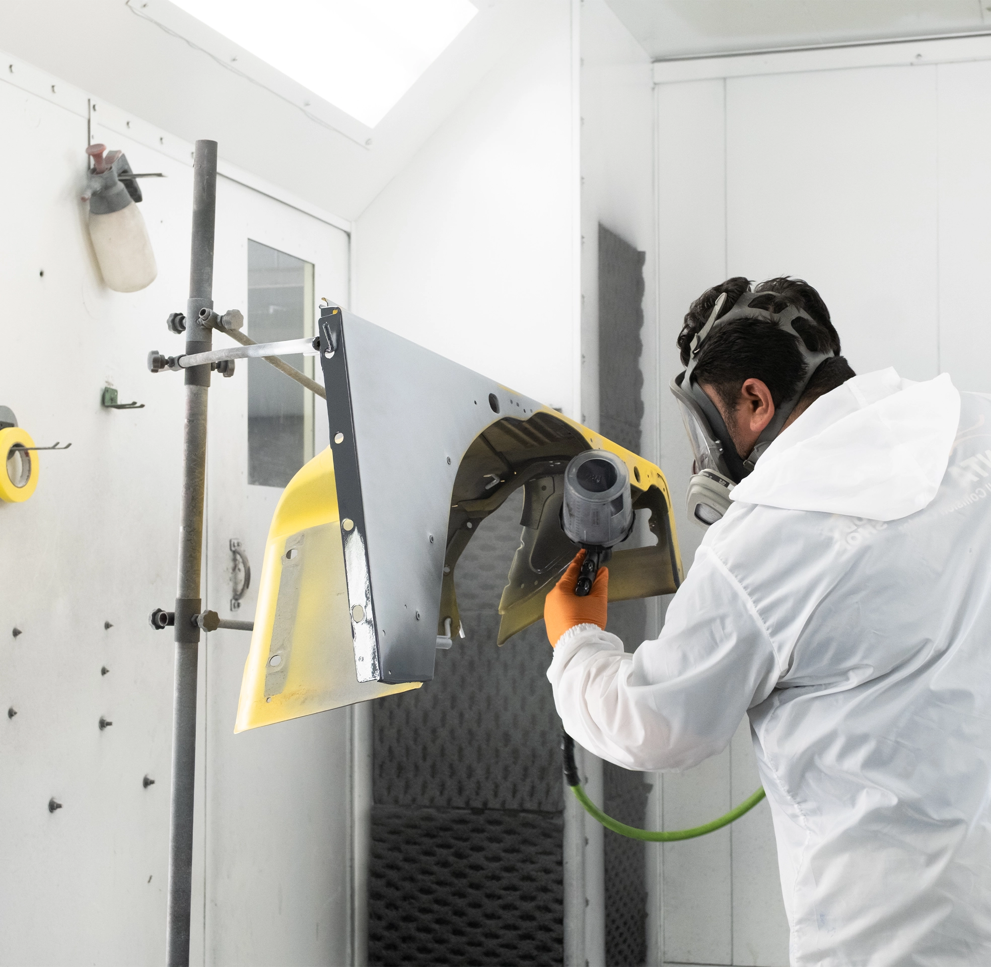 Automotive worker spray painting car parts